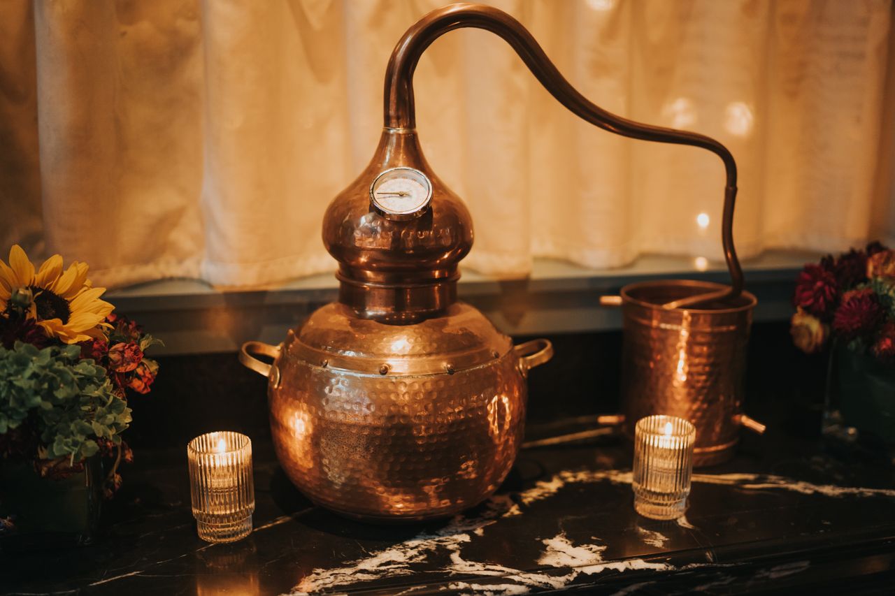 A copper still, adorned with candles and floral arrangements, creating a vintage ambiance.