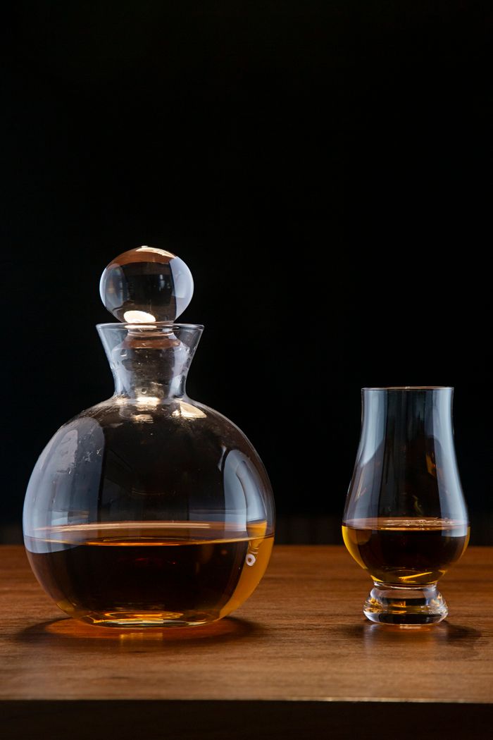A stylish display of whiskey in a decanter and glass on a wooden surface.