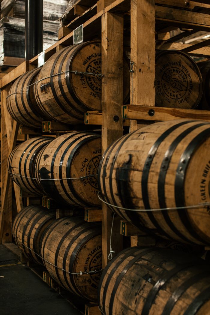 A vertical shot of wooden barrels neatly stacked in a distillery's storage room.