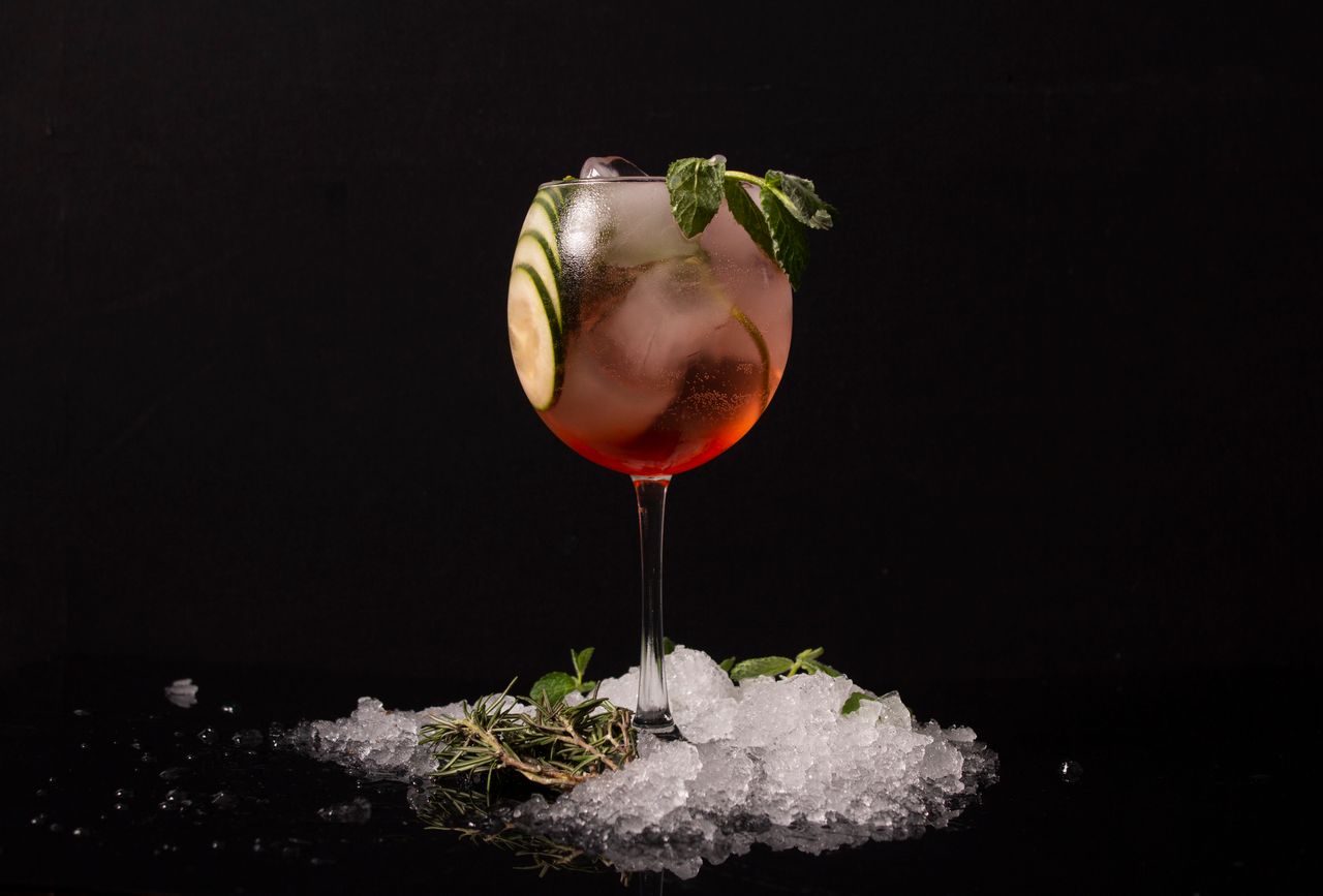 ours-journey A refreshing cocktail in a glass with cucumber and mint garnish, surrounded by ice.
